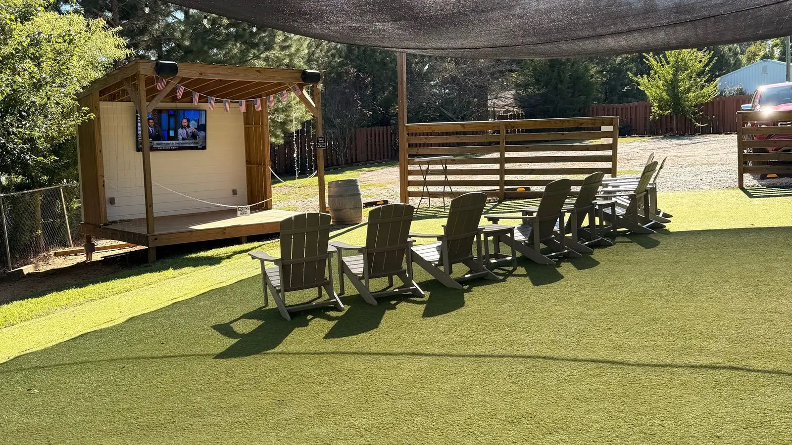 Artificial turf yard with Adirondack chairs and the stage at Lazy Creek Taphouse