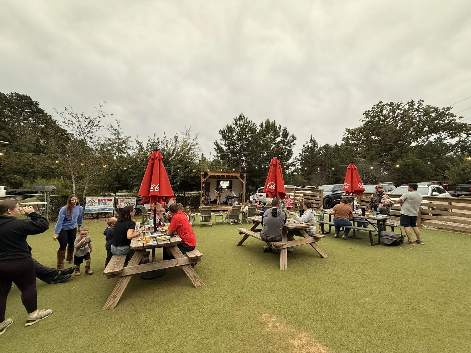 Families at picnic tables under red umbrellas in the yard
