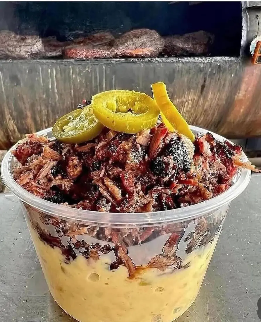 Ironwood BBQ smoked meat over mac and cheese, with the smoker behind it